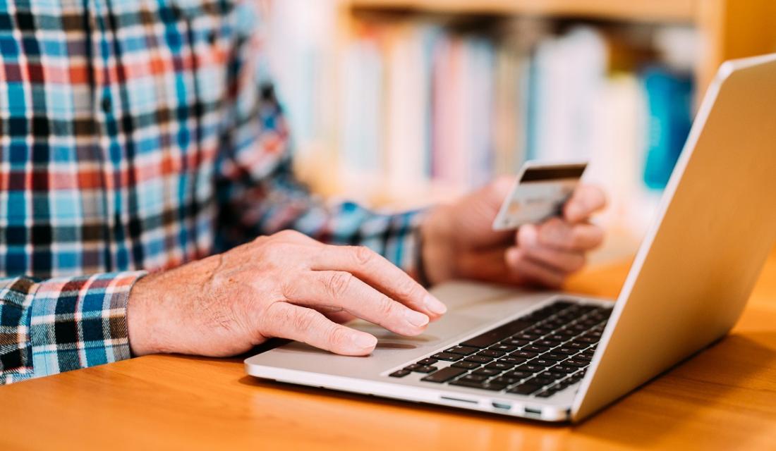 Jemand sitzt am Laptop und gibt seine Kartennummer ein.