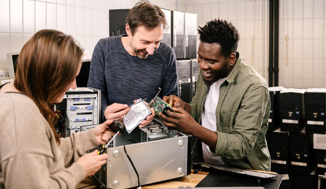 Drei Personen reparieren einen Computer.