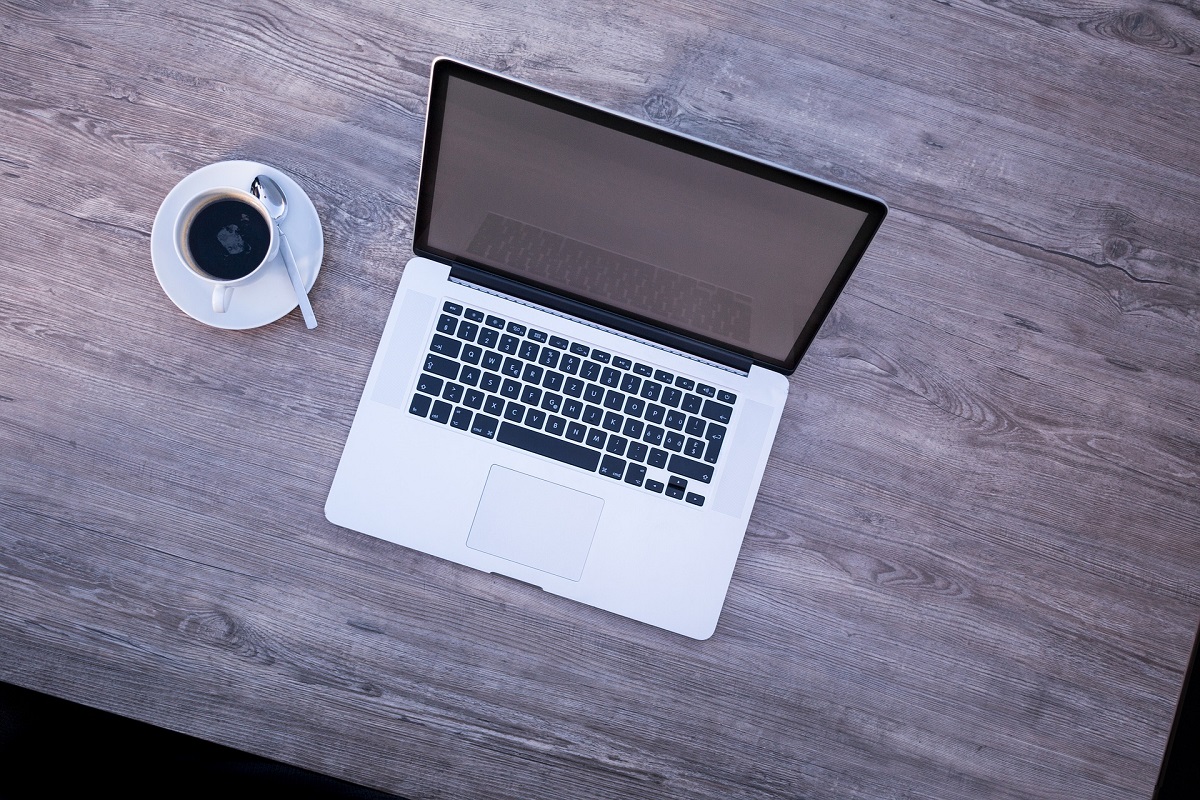 Laptop und Kaffeetasse auf einem Schreibtisch.