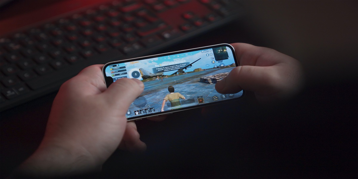 Kinderhände halten ein Smartphone, auf dem ein Spiel gespielt wird.
