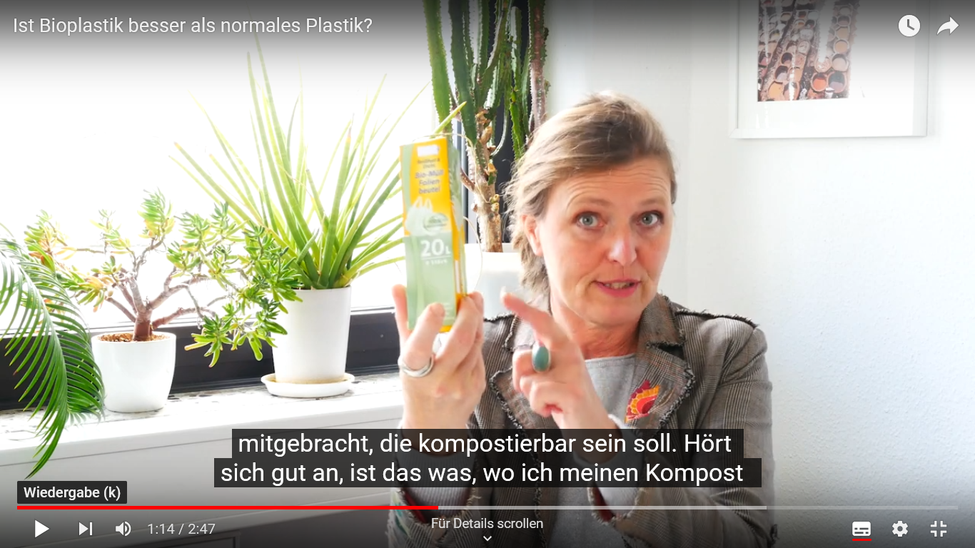 Screenshot eines Videos mit einer Frau, die eine Packung Plastiktüten aus Bioplastik hochhält.