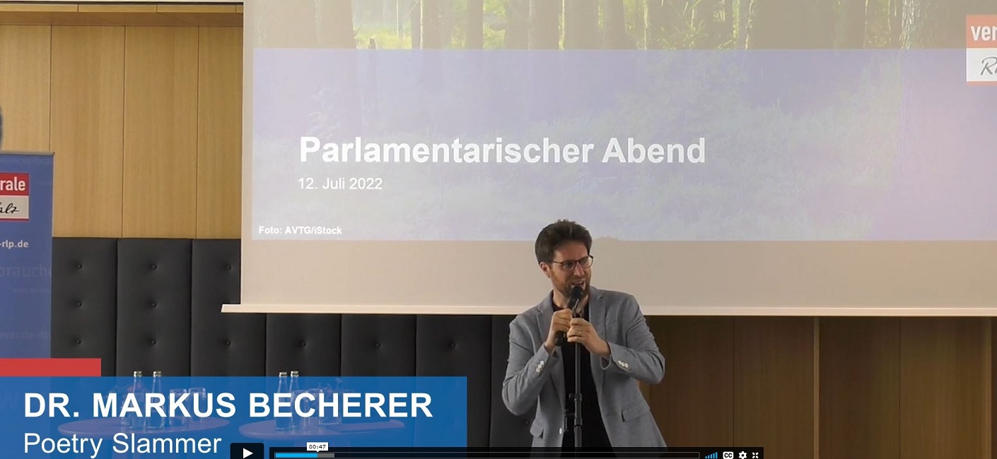 Ein Mann steht auf einer Bühne und hält einen Vortrag.