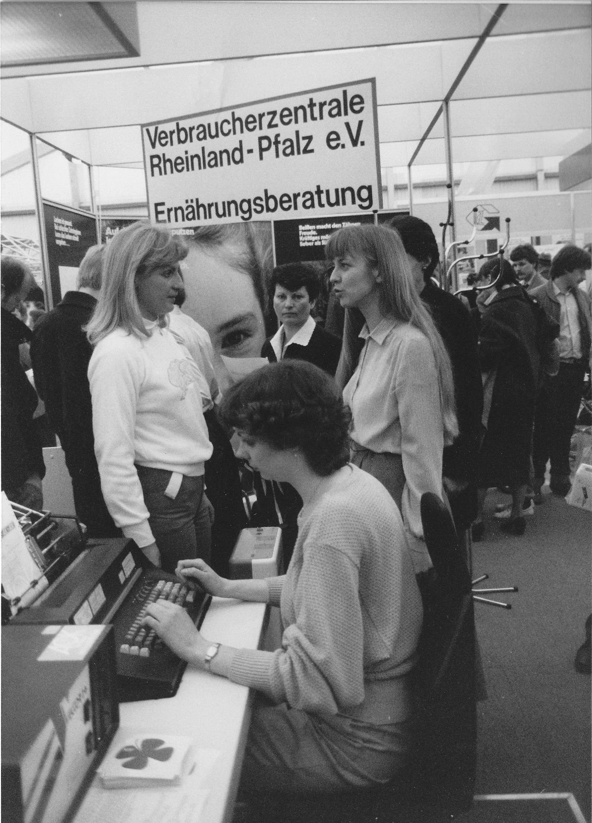 Frauen unetrhaltens ich an einem Messestand.