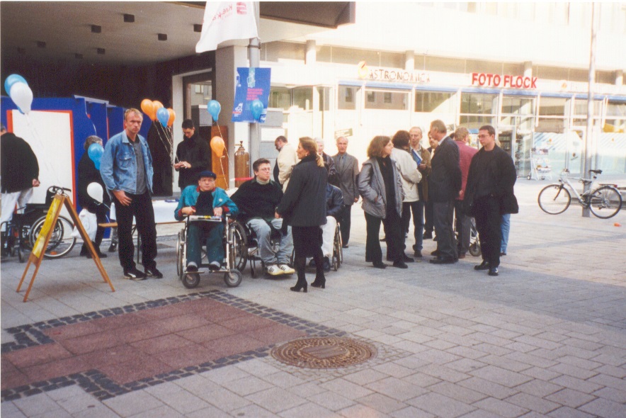 Menschen mit udn ohne Rollstuhl auf der Straße.