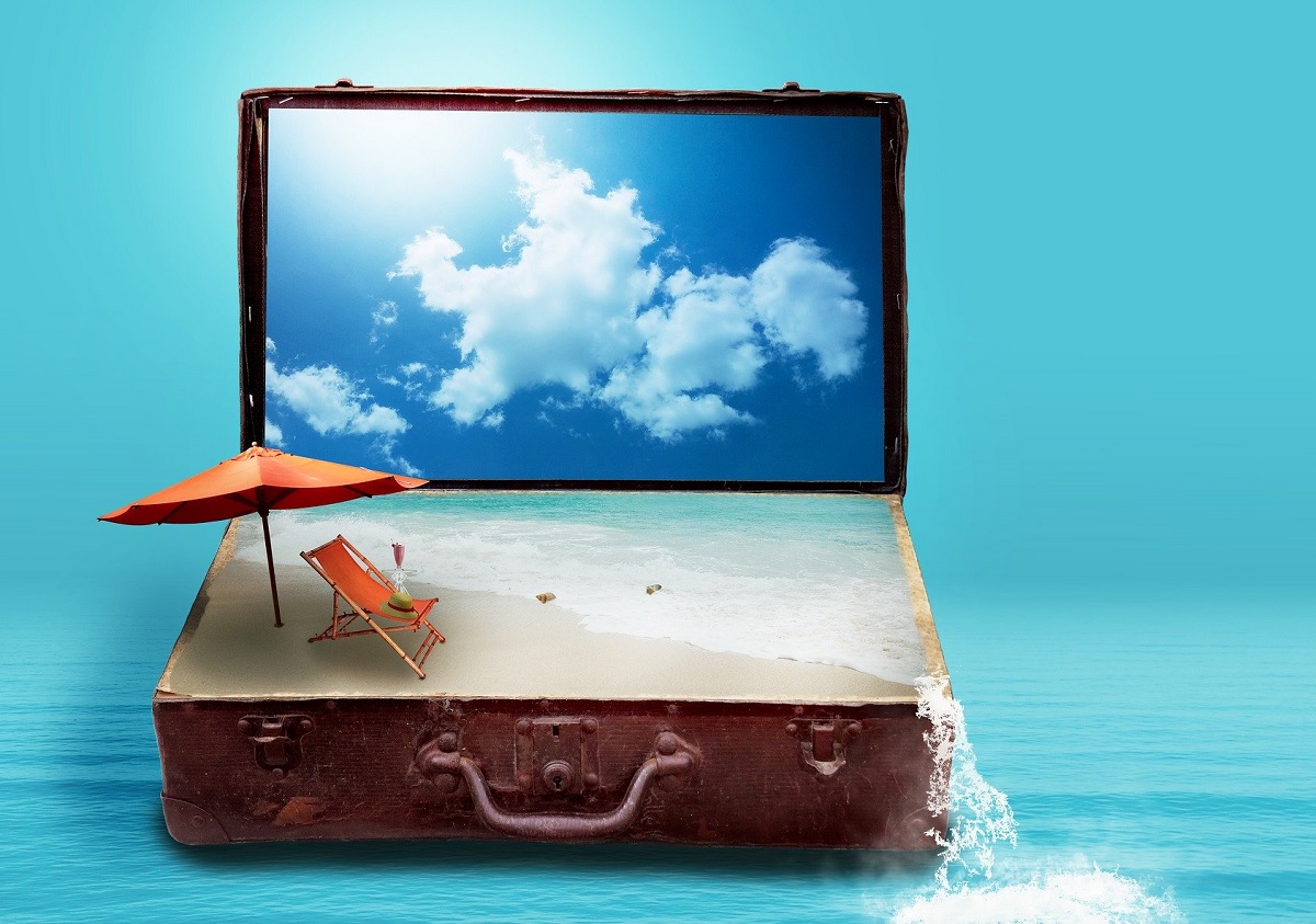 Ein geöffneter Koffer mit Strand, Sonnenschirm und Meer in der Unterseite des Koffers.