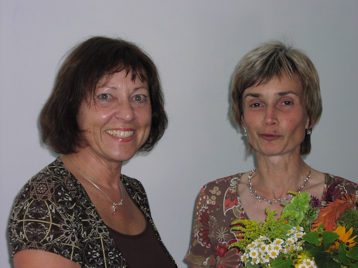 Eine Frau bekommt von einer anderen Frau einen Blumenstrauß überreicht.