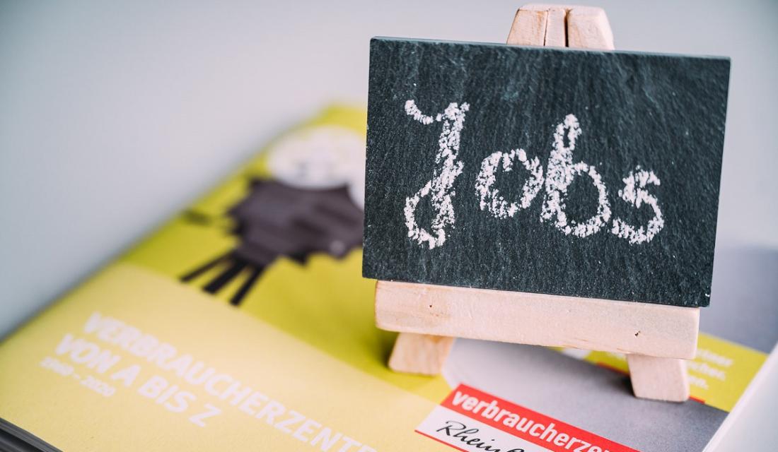 Auf einem kleinen Buch steht eine kleine Schieferntafel mit dem Wort Jobs drauf.