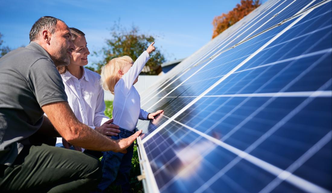 Eine Familie zeigt auf eine Solaranlage auf dem Dach.