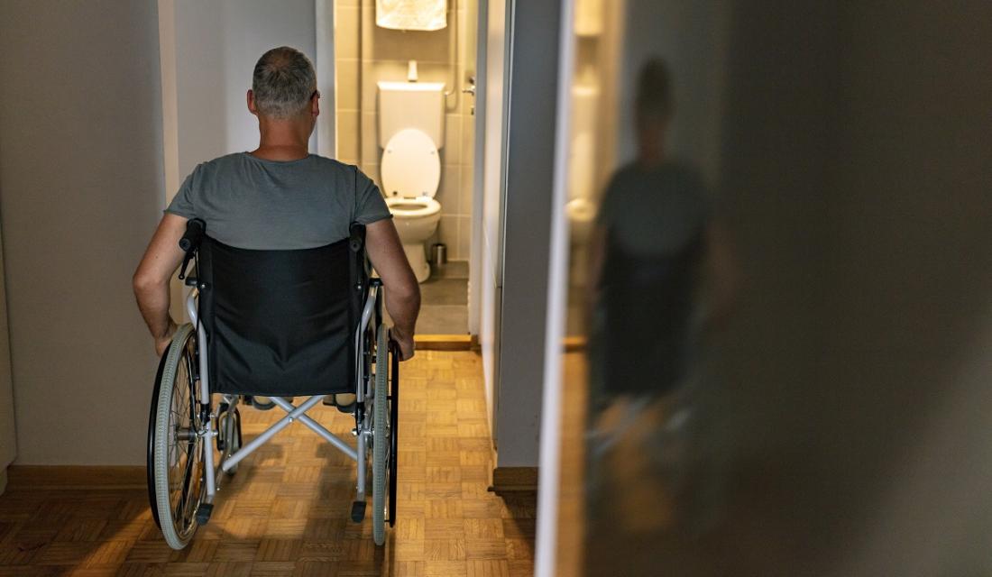 Mann im Rollstuhl möchte auf die Toilette, die allerdings nicht groß genug für einen Rollstuhl ist.