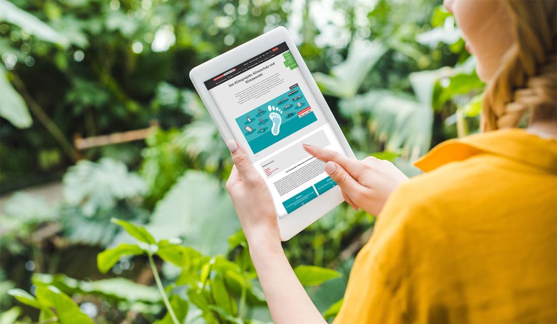 Frau mit Tablet im Grünen.