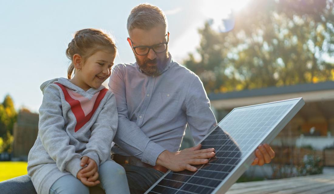 Vater und Tochter schauen sich ein Solarmodul für den Balkon an.