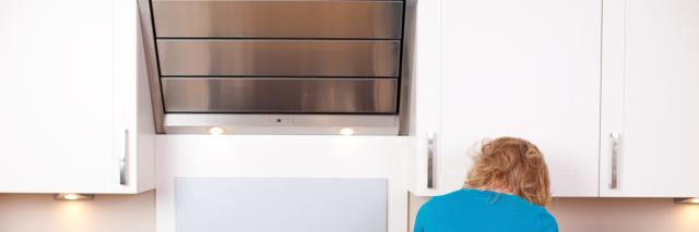 Eine Frau steht vor einer Dunstabzugshaube in der Küche