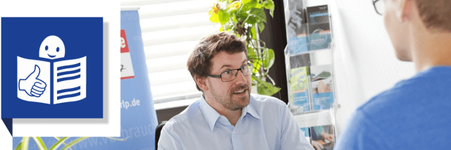 Zwei Personen an einem Schreibtisch im Gepräch.