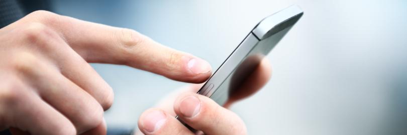 Ein Mann hält ein Smartphone in der Hand und tippt mit dem Zeigefinger darauf.