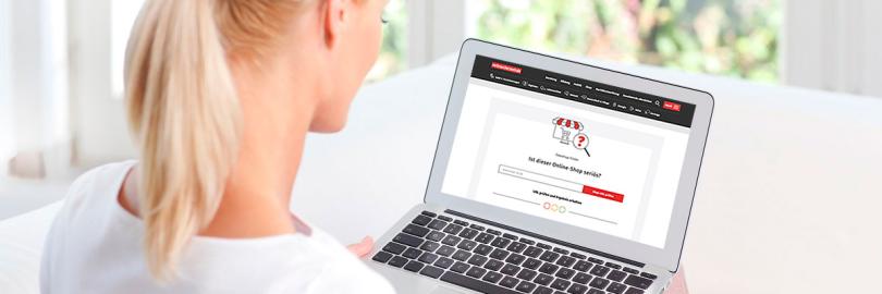 Frau sitzt mit einem Laptop am Tisch.