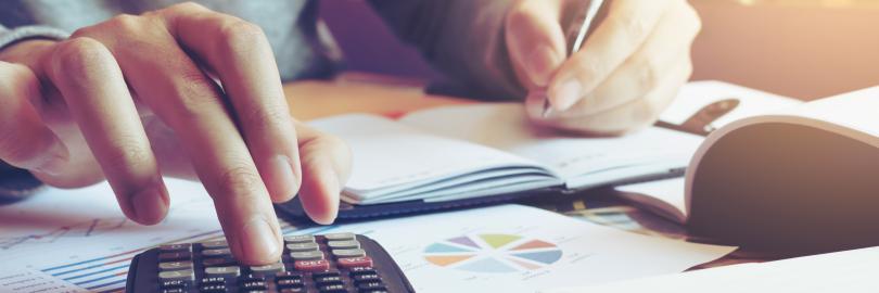 Hände mit Stift und Taschenrechner