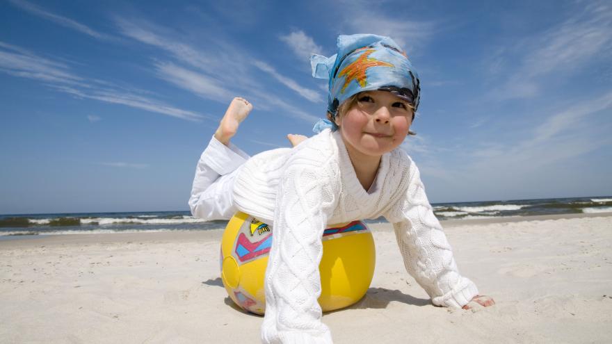 Ein Kind am Strand mit einem aufblasbaren Ball