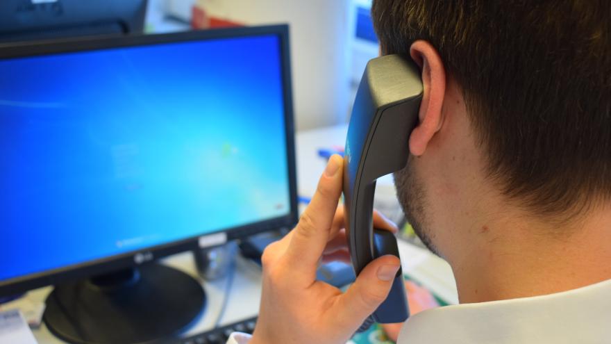 Mann mit Telefonhörer sitzt vor PC