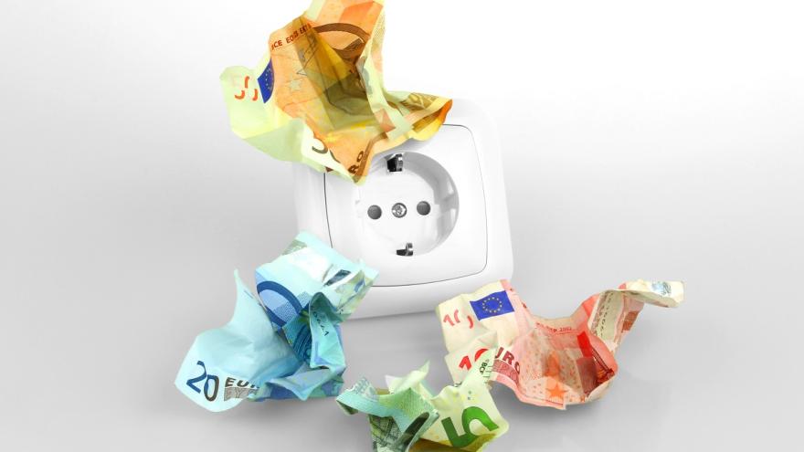 Zerknittertes Geld vor einer Steckdose. 