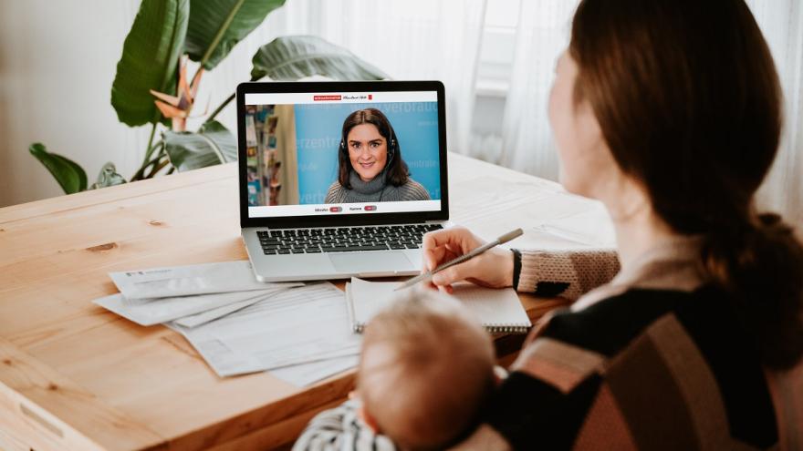 Frau sitzt mit Laptop an einem Tisch und unterhält sich per Video-Chat.