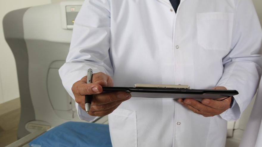 Ein Arzt im weißen Kittel füllt einen Antrag aus