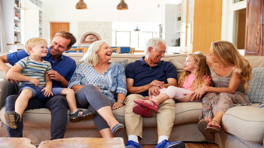 Eine Familie mit Kindern und Großeltern sitzt auf dem Sofa