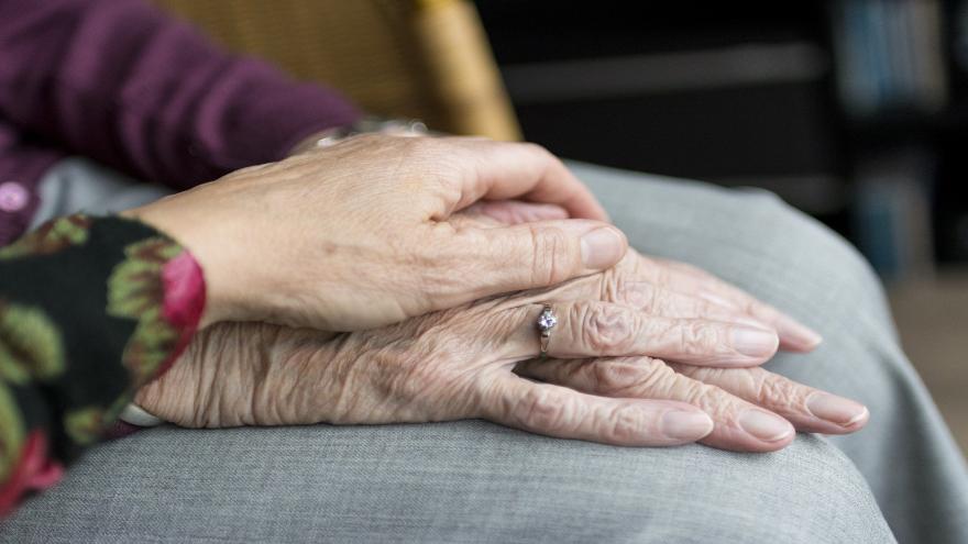 Eine jüngere Hand hält die Hand eines älteren Menschen.
