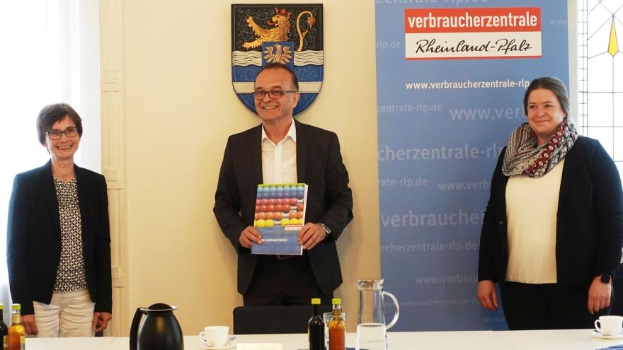 Drei Personen stehen vor einer Wand und blicken in die Kamera.