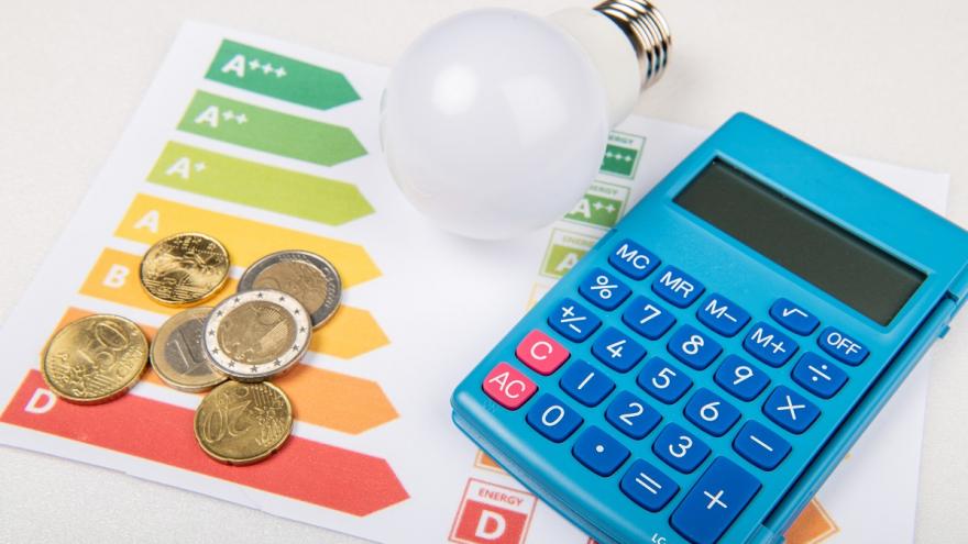 Geld und Ein Taschenrechner liegen auf einer Energieverbrauchsskala