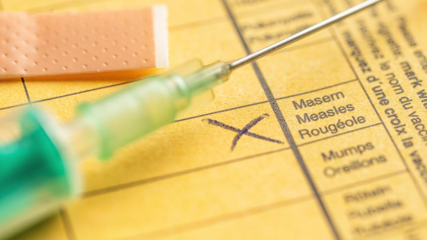 Eine Spritze mit Impfstoff gegen Masern liegt auf einem offenen Impfpass