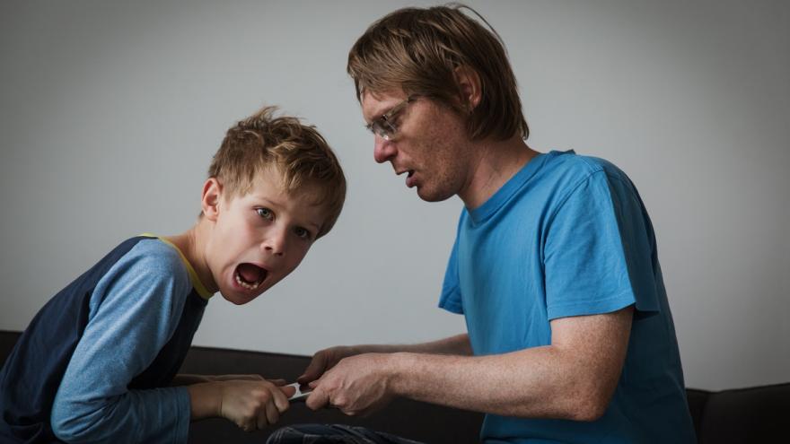 Vater und Sohn streiten sich um ein Tablet. Der Vater will es dem Sohn wegnehmen, der das nicht will.