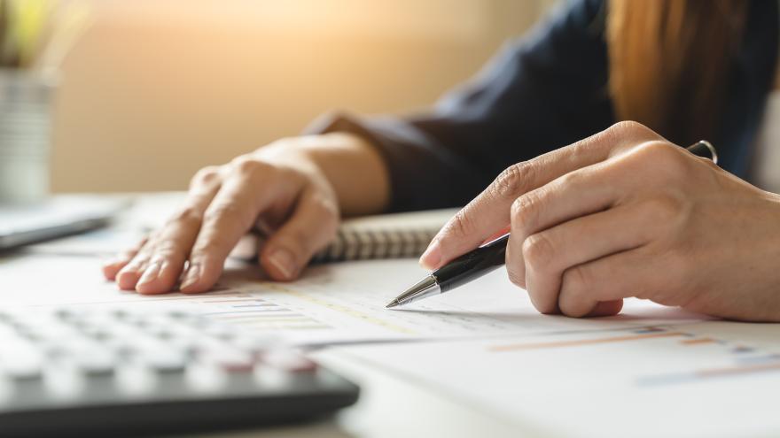 Ein Mann hält einen Stift in der Hand und rechnet Fondskosten aus