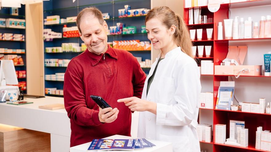 Eine Apothekerin berät einen Kunden zu einer Gesundheitsapp.