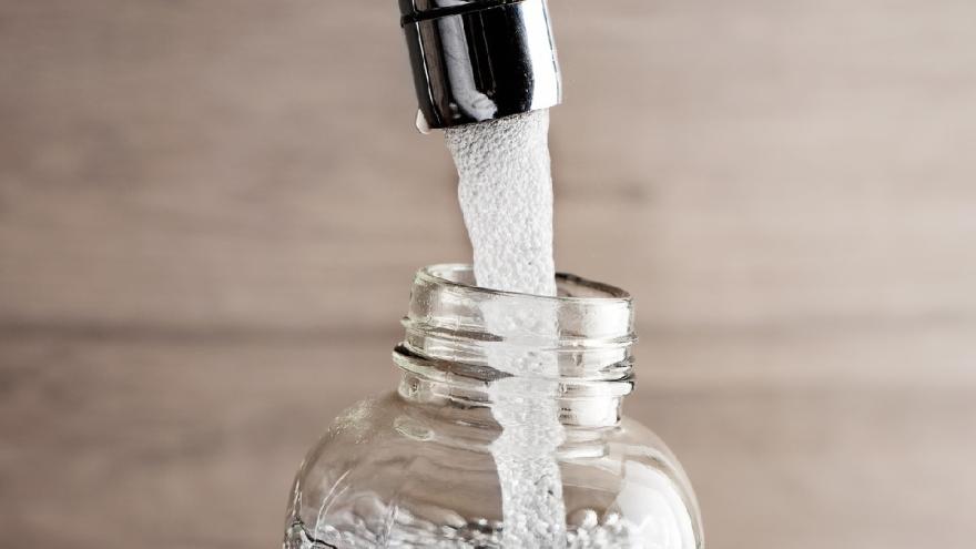 Ein Wasserhahn, aus dem Wasser in eine Flasche fließt.