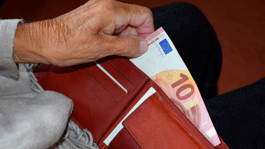 Hand einer älteren Frau zieht einen 10 Euro-Schein aus einem Geldbeutel.