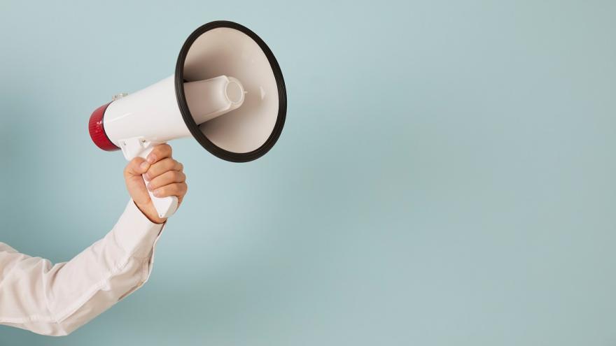 Ein Arm hält ein Megaphone ins Bild. 