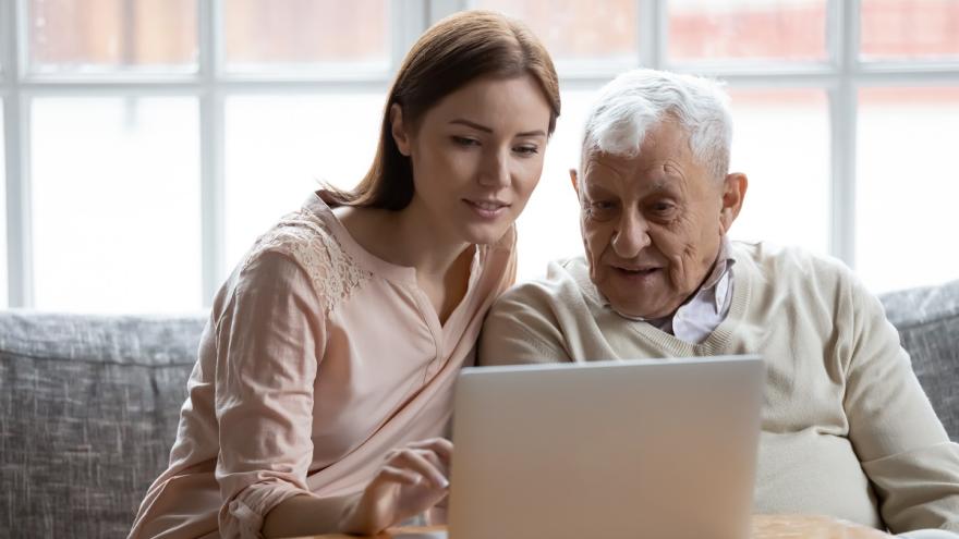 Ein Vater und seine erwachsene Tochter sitzen zusammen vor einem Laptop.