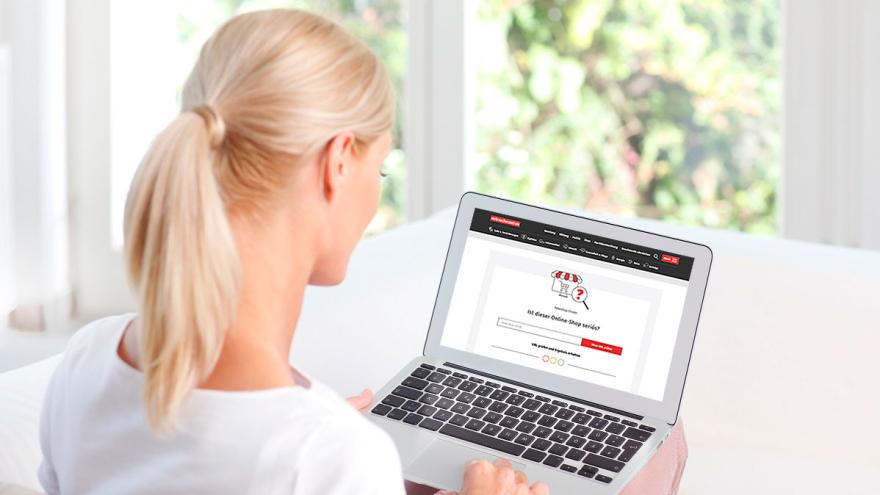 Frau sitzt mit einem Laptop am Tisch.