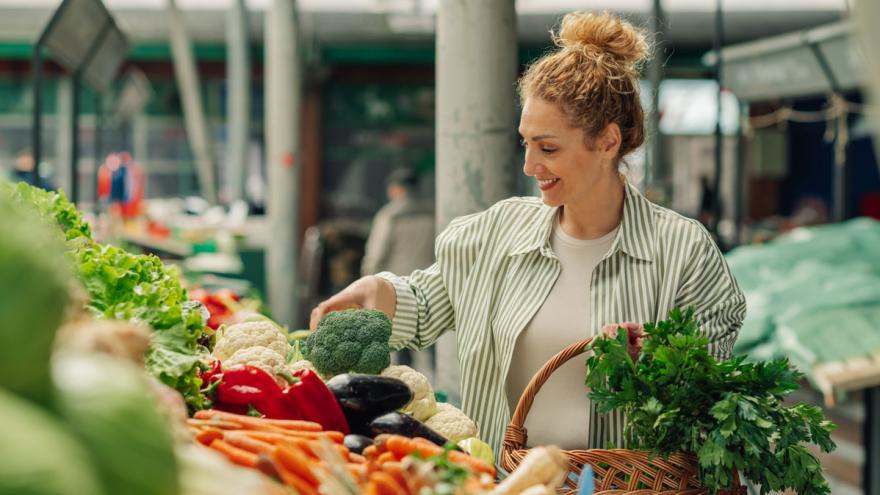 Frau an einem Marktstand mit Obst und Gemüse