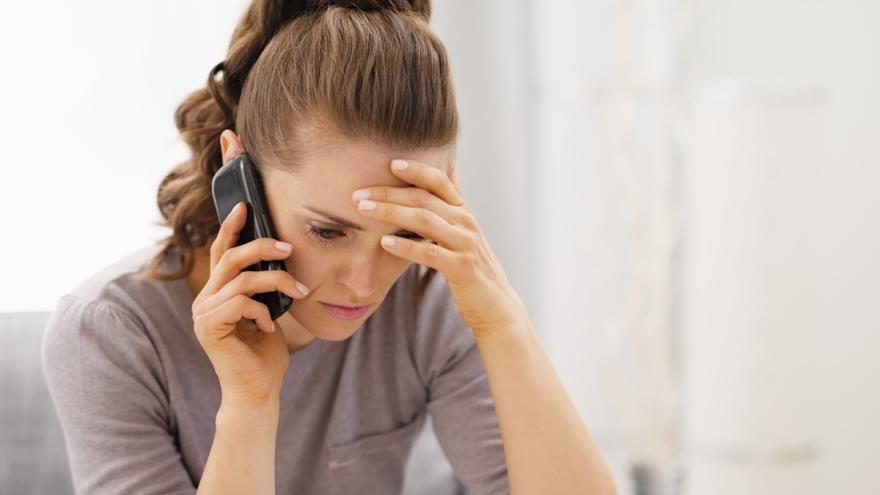 Eine Frau am Telefon mit schlehten Nachrichten.