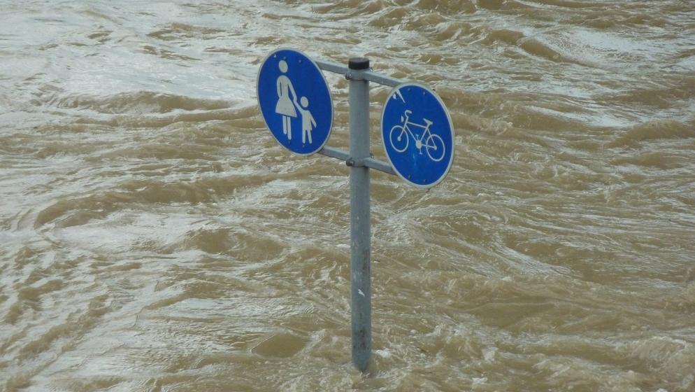 Ein Straßenschild steht fast komplett im Wasser.