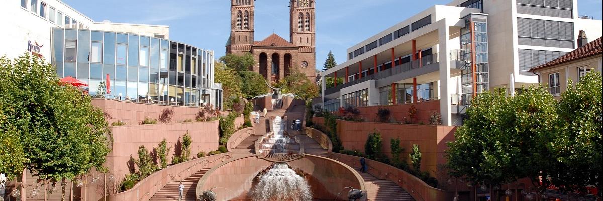 Ein großer Platz, im Hintergrund stehen zwei Türme, rechts und links sind Bürogebäude.