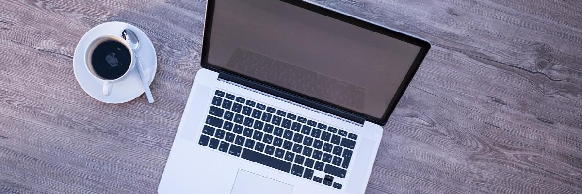 Laptop und Kaffeetasse auf einem Schreibtisch.
