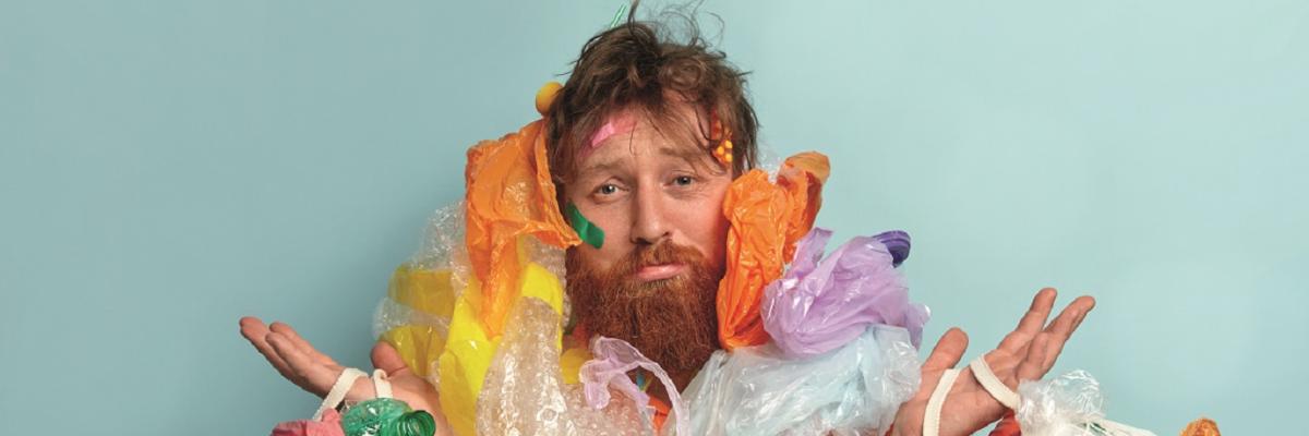 Mann mit Plastiktüten und Plastikflaschen behängt.