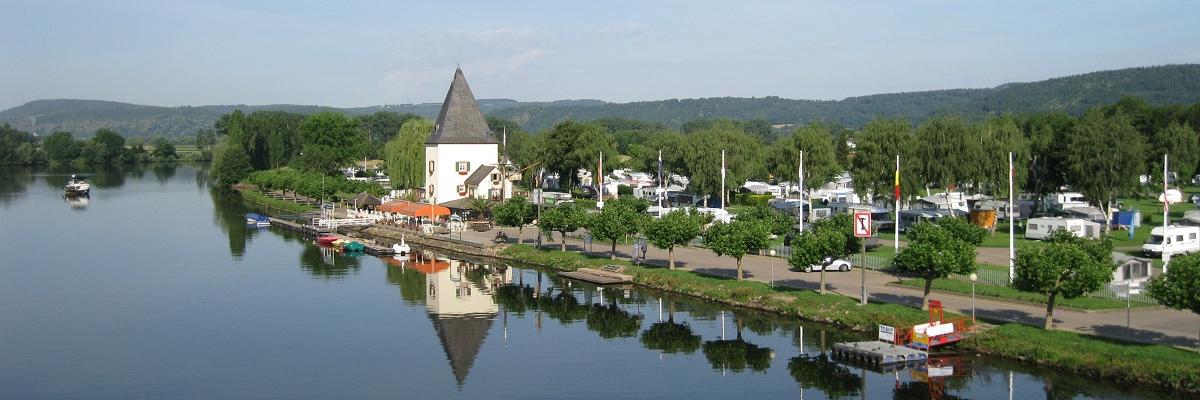 Links im Bild fließt ein Fluss; rechts im Bild ist eine Uferpromenade mit einem Turm.