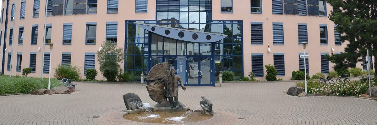 Ein Bürogebäude mit einem weiten Platz davor. 