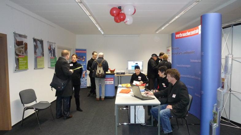 Ein Infostand in einem Raum und Besucher.