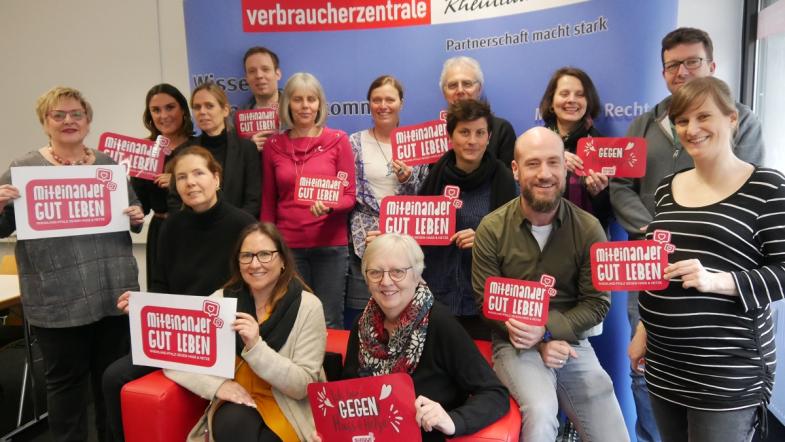 Ein Gruppenbild von Menschen rund um ein rotes Sofa.