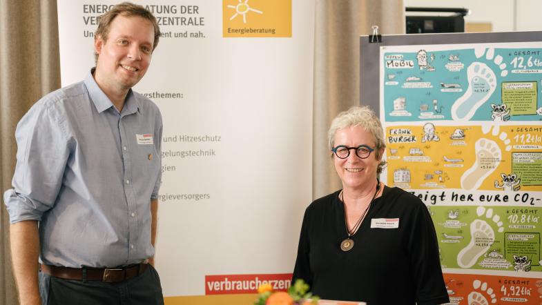 Ein Mann und eine Frau an einem Messestand. Sie lächeln in die Kamera