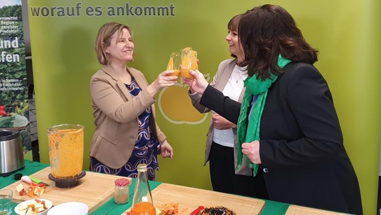 Drei Frauen stoßen mit einem Gemüsesmoothie an.